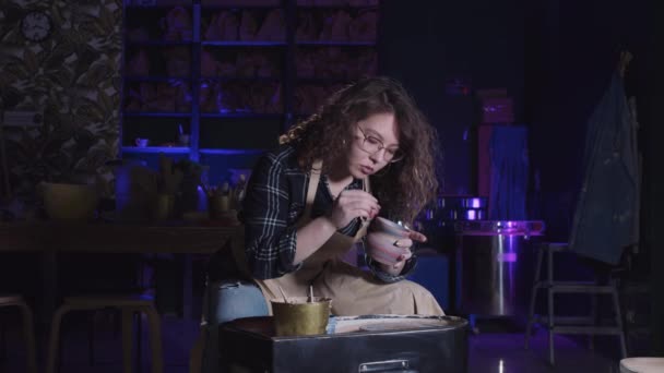 Mujer con el pelo rizado limpiando la superficie de la nueva olla fresca hecha de arcilla — Vídeos de Stock