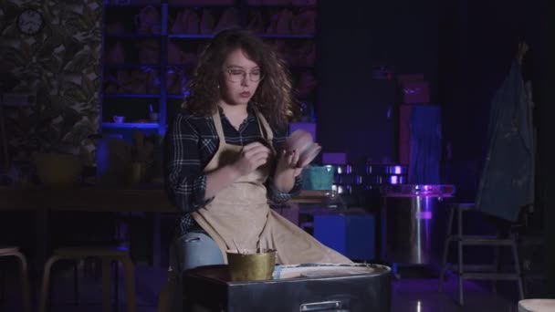 Donna con capelli ricci lavoro di finitura con una pentola di argilla — Video Stock