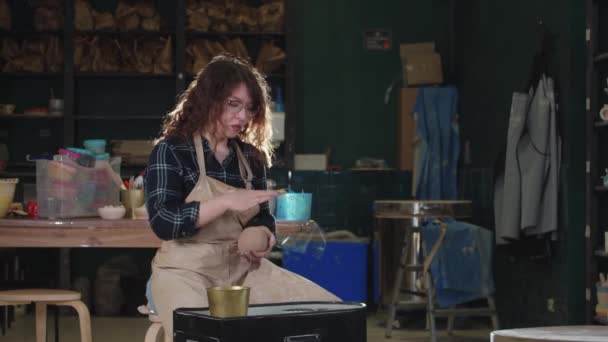 Çömlekçilik - kıvırcık saçlı bir kadın top şeklinde kuru kil yapar ve çömlekçi çarkına koyar. — Stok video