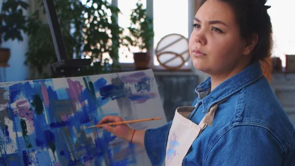 Una mujer artista dibujando una pintura y mirando hacia un lado —  Fotos de Stock