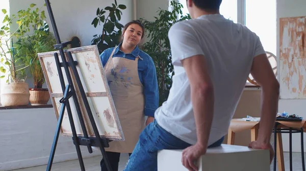 Uma mulher pintora desenhando em uma tela tomando um modelo masculino como referência — Fotografia de Stock