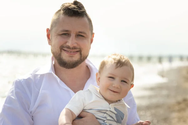 幸せな父の休暇-笑顔男立ってビーチに保持彼の小さな赤ちゃんの息子 — ストック写真