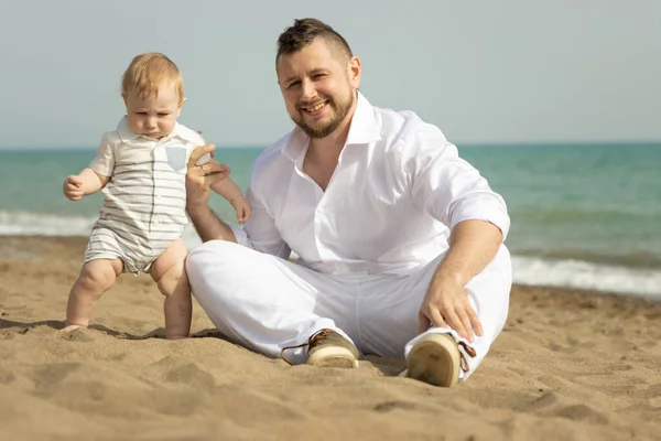 Heureux père assis sur une plage avec son petit fils — Photo