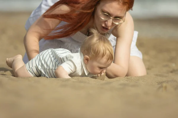 Familienurlaub - kleiner Junge versucht, den Sand zu essen und seine Mutter hält ihn auf — Stockfoto