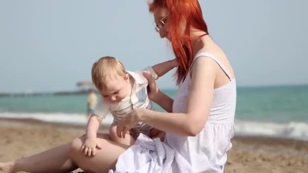 Šťastná matka se svým synem sedí na pláži — Stock video
