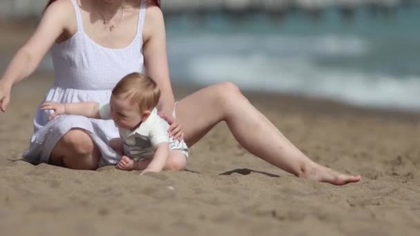 Šťastná matka se svým malým synem hrát s pískem na pláži — Stock video