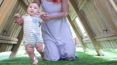 Anne küçük oğluna el ele tutuşarak yürümeyi öğretiyor.