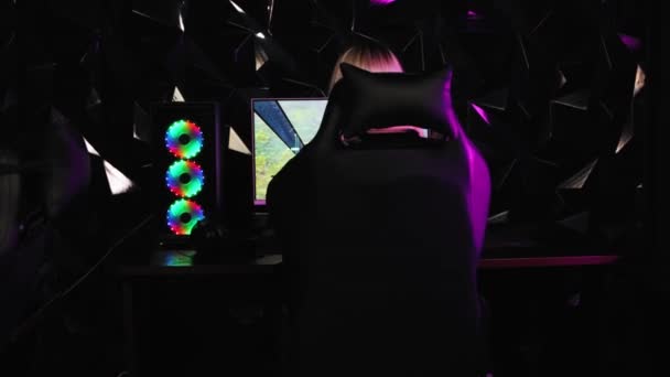 Szőke és csinos játékos lány elfordul a PC monitor és nézi a kamera neon világítás — Stock videók