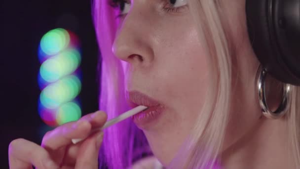 Blonde sexy gamer girl sucking a lollipop — Stock Video