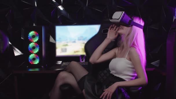 Jong blond gamer meisje zitten in een stoel dragen VR bril — Stockvideo