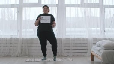 Kendine güveni tam şişman bir kadın, elinde bir tabelayla bir plaka tutuyor.