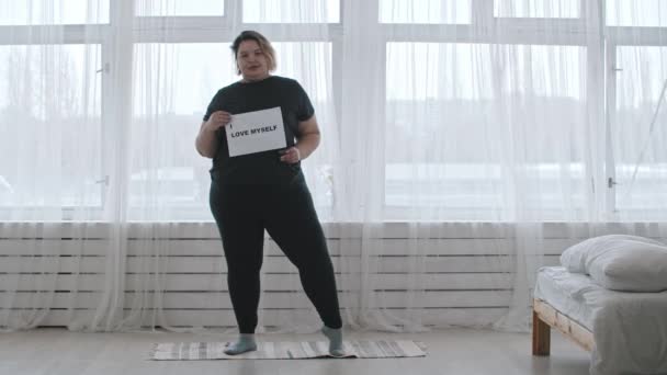 Έννοια θετικότητα σώματος - μια παχουλή γυναίκα κρατά ένα σημάδι με την επιγραφή Αγαπώ τον εαυτό μου — Αρχείο Βίντεο