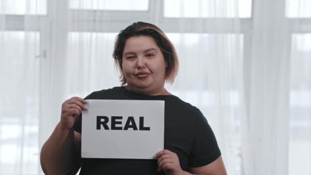 コンセプトボディポジティビティ-脂肪カリスマ女性は碑文とサインを保持していますREAL -カメラを見て — ストック動画