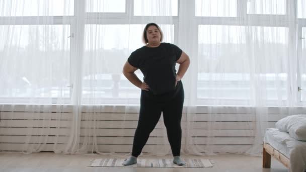Толстая женщина делает разогрев упражнений дома — стоковое видео