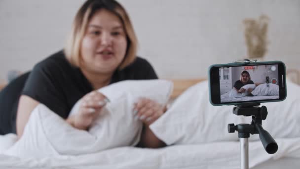 Een zelfverzekerde vrouw met overgewicht feminist liggend in bed en pratend op een video voor haar volgelingen over positiviteit van het lichaam — Stockvideo