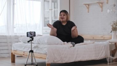 Kendine güvenen aşırı kilolu bir feminist yatakta oturmuş videoda feminizm ve vücut pozitifliği hakkında konuşuyor.