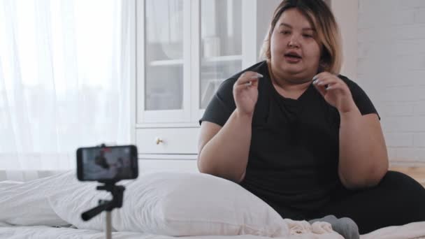 Una mujer gorda confiada sentada en la cama y hablando sobre su experiencia sobre el feminismo y la positividad corporal en video — Vídeos de Stock