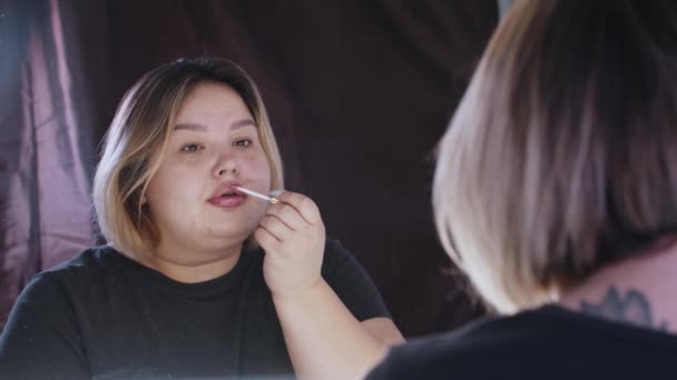 Eine übergewichtige Frau trägt Lipgloss auf ihre Lippen auf — Stockvideo
