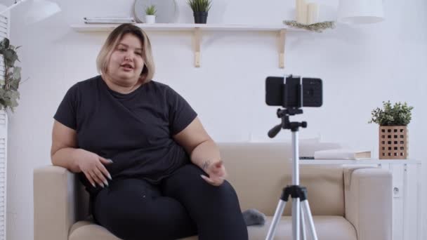 Vücut pozitifliği - koltukta uzanmış kendine güvenen aşırı kilolu kadın feminist ve takipçileri için vücut pozitifliği hakkında bir video hazırlıyor. — Stok video