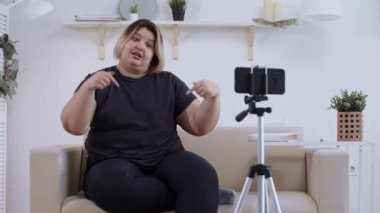 Vücut pozitifliği. Kanepede uzanan ve telefonunda vücut pozitifliği hakkında video çeken kendine güvenen şişman kadın feminist.