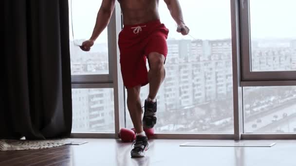 Atletický muž bez trička skákání přes provaz ve studiu s panoramatickými okny — Stock video