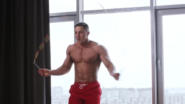 Atletische shirtloze man professioneel springen over het touw in de studio met panoramische ramen — Stockvideo