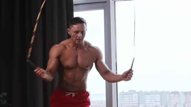 Deportes - atlético hombre musculoso sin camisa saltando profesionalmente sobre la cuerda en el estudio con ventanas panorámicas — Vídeos de Stock