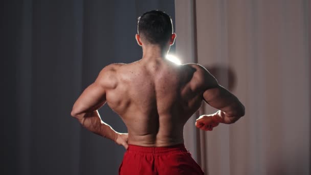 Sportovní trénink - atletický svalnatý muž bez trička ukazující svaly zezadu — Stock video