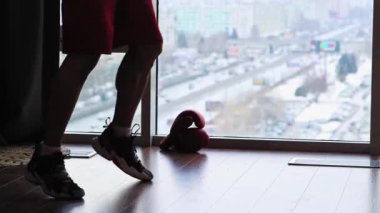 Stüdyoda panoramik pencereli spor eğitimi. Gölgeli, üstsüz, kaslı bir adam boks yapıyor.