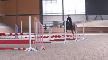 Binicilik sporu. Siyah elbiseli bir atlı kadın engellerin üzerinden atlıyor.