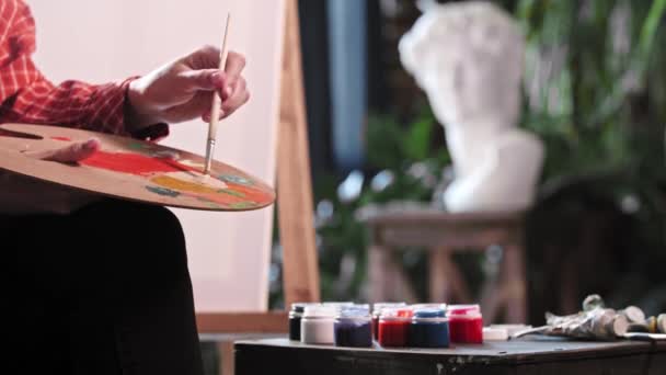 Une jeune femme dans un atelier d'art mélangeant une couleur beige sur la palette — Video