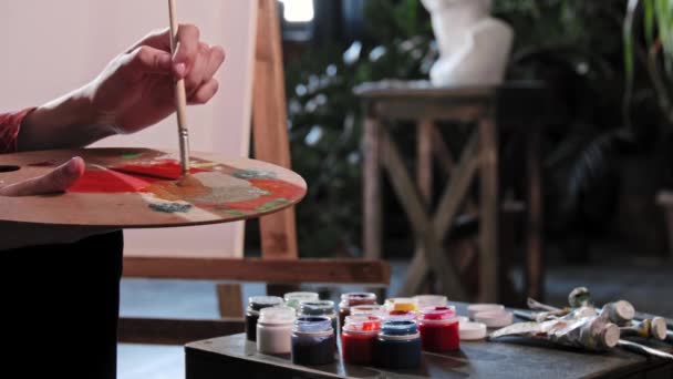 A young woman artist mixing colors on the palette in art workshop — Stock Video