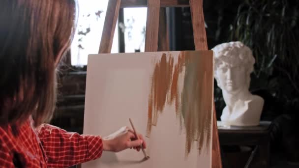 Une jeune jolie artiste dans un atelier d'art - appliquer des couleurs sur une toile — Video