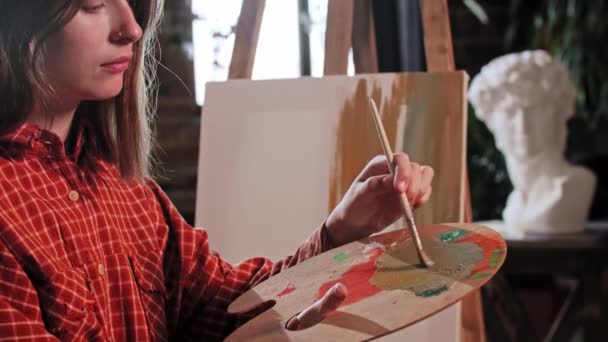 木製のパレットに色を混合若い美しい女性アーティスト — ストック動画