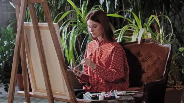 Artista en un taller - joven hermosa mujer dibujando una pintura con colores — Vídeos de Stock