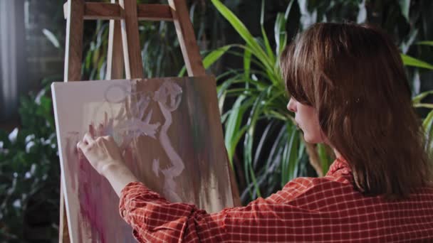 Ung kvinna ritar en abstrakt målning på en duk — Stockvideo