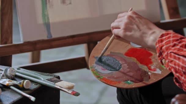 Artista joven mezclando un color grisáceo en una paleta — Vídeo de stock