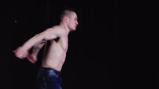 Jonge opgepompte man in spijkerbroek springt en raakt zijn tenen in de lucht — Stockvideo