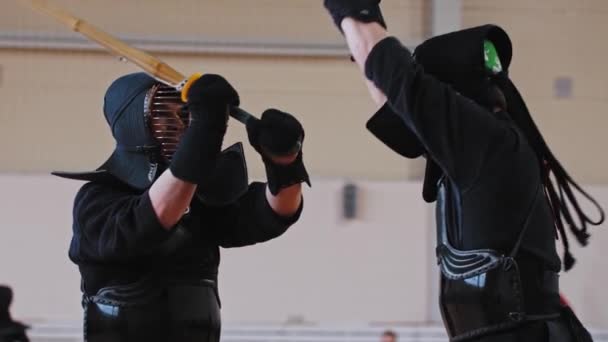 RUSSIA, KAZAN 24-04-2021: Kendo toernooi binnen - twee mannen in zwarte traditionele kostuums met een duel op bamboe zwaarden — Stockvideo