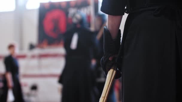 Kendo toernooi - een man in nationale zwarte kleren wacht op zijn beurt met een houten stok — Stockvideo