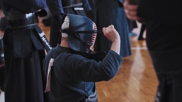 Torneo de Kendo - un hombre en traje negro atando las bandas en su casco — Vídeo de stock