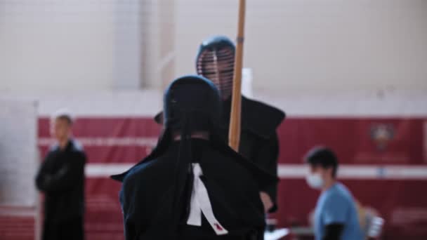 RUSSIA, KAZAN 24-04-2021: Kendo toernooi - twee vechters in zwarte kostuums met een duel op bamboe stokken — Stockvideo