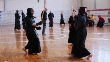 RUSSIA, KAZAN 24-04-2021: Okulun spor salonunda Kendo turnuvası - iki adam bambu çubuklarıyla kavga ediyor ve yargıç onları izliyor