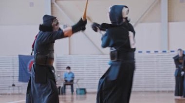 RUSSIA, KAZAN 24-04-2021: Kendo turnuvası - Japon dövüş sanatı - geleneksel siyah elbiseli iki dövüşçü bambu kılıçlarla birbirleriyle dövüşüyor