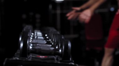 Spor salonundaki halterden dambıl alan insanlar.