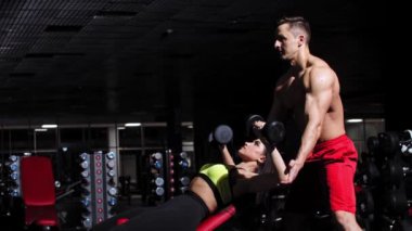 Spor salonunda ona yardım eden bir kadın ellerini çalıştırıyor.