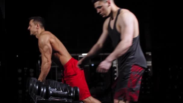 Hommes et femmes prenant haltères du stand dans la salle de gym — Video