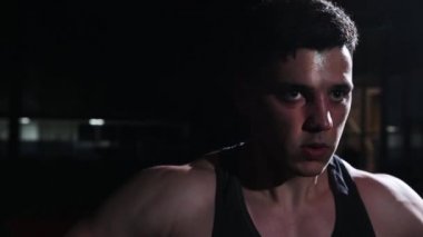 Beden eğitimi - genç formda bir adam dambılları kaldırıyor ve ellerini çalıştırıyor.