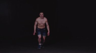 Kot şortlu genç pompalı adam koşuyor ve takla atıyor.