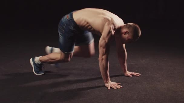 Giovane pompato ragazzo in pantaloncini di jeans facendo esercizi di resistenza per il suo corpo salta e cade sulle sue mani — Video Stock